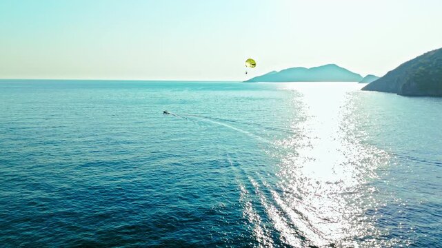 Aerial view off Oludeniz Blue Lagoon, Turkey sea. Sunlight shines on blue water with distant mountains and a calm summer travel mood. Tourist paragliding in Turkey.