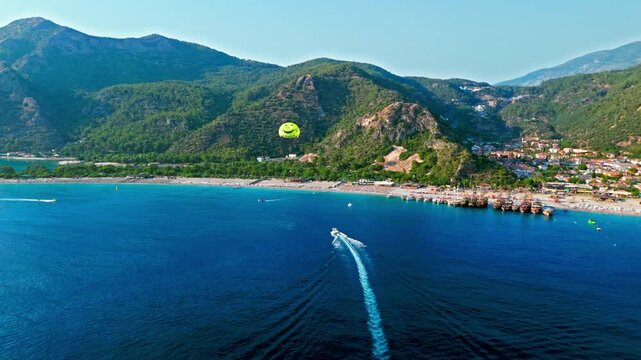 Drone view off Oludeniz Blue Lagoon, Turkey coast. Boat wake, blue sea and green mountains create a scenic summer adventure view.