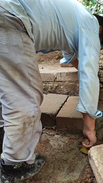 Mason bending over to seal bricks with cement mixture