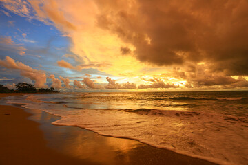 Obraz premium Golden sunset paints sky and sea in warm hues. Silent beach invites calm, reflection, and peace.