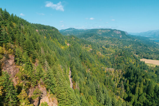 Ragged mountain with steep rocky slopes but covered everywhere else with a dense forest on a clear day, with other peaks fading into the distance.
