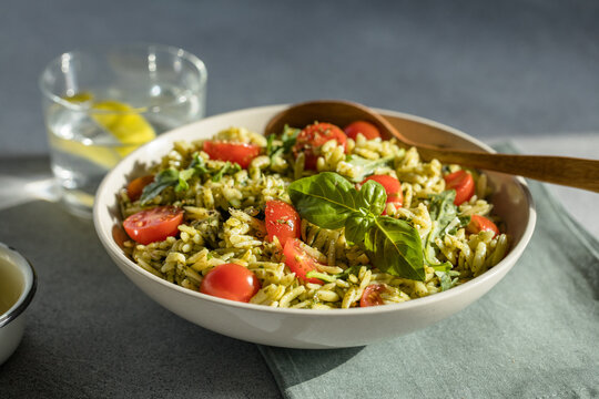 Salad with orzo pasta, arugaula, pesto sauce, and sun-dried tomatoes