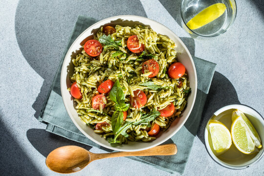 Salad with orzo pasta, arugaula, pesto sauce, and sun-dried tomatoes