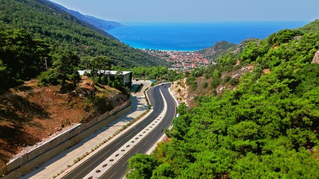 Aerial view of Oludeniz, Turkey mountain road and coast. Winding highway, green hills and blue sea create a scenic Mediterranean travel view.