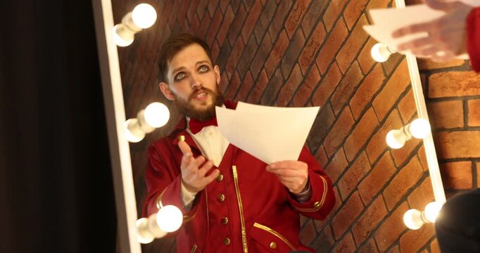 Actor with script rehearsing his lines near mirror in dressing room, low angle view
