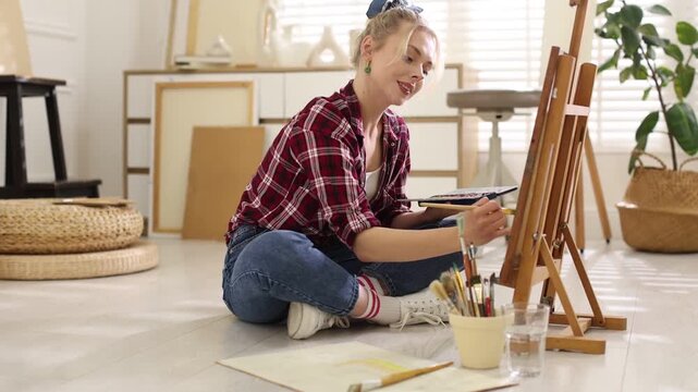 Beautiful woman painting on canvas in studio, camera moving in