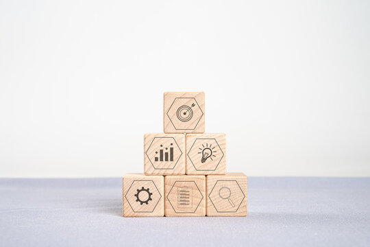 Pyramid of wooden cubes with  icons for target, growth, idea, management, and research.  business strategy, Financial Management and Business Planning Concept.