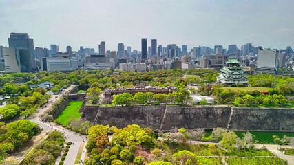 Naklejka premium Majestic Osaka Castle surrounded by modern skyscrapers from above