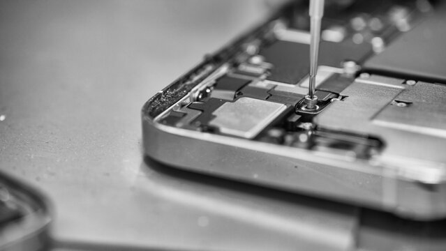 Skilled mobile phone repair specialist working on disassembled smartphone internals in lab