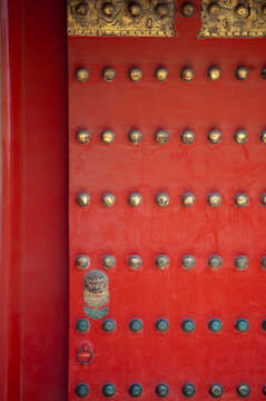 Close-up of a traditional red door with golden studs