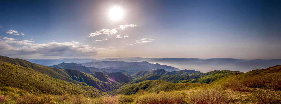 Sunny day over mountainous landscape with green hills and clear sky