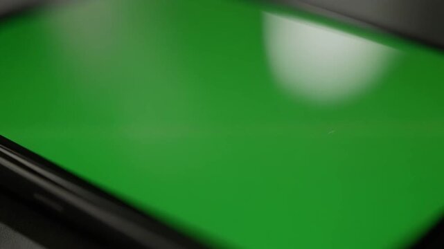 Close-up view of a modern smartphone with a vibrant green screen.
