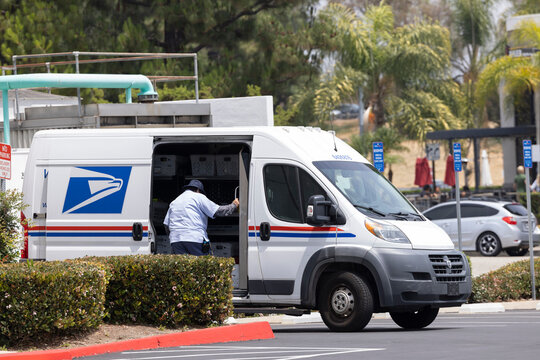 Fullerton, California, USA - May 2, 2026: A USPS Postal worker walks into the back of a delivery van to pick up mail.