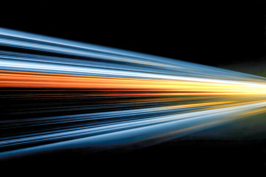 Dynamic colorful light streaks creating a sense of speed and motion against a dark background, illustrating futuristic technology and energy flow concepts
