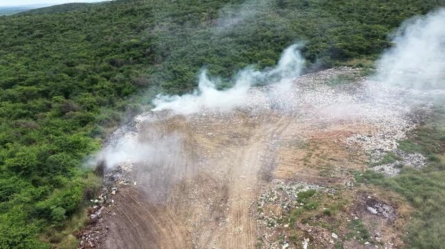 Lix&atilde;o a c&eacute;u aberto com fuma&ccedil;a t&oacute;xica e degradante impacto ambiental. Vista panor&acirc;mica de aterro sanit&aacute;rio irregular (lix&atilde;o) liberando fuma&ccedil;a no meio da vegeta&ccedil;&atilde;o. lixo se acumula, causando polui&ccedil;&atilde;o.