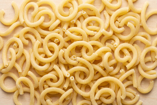 Uncooked gramigna pasta with a unique twisted shape on a wooden background for cooking