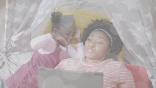 Mother tapping tablet bokeh showing over tent, child snuggling then giggling for education cuddling