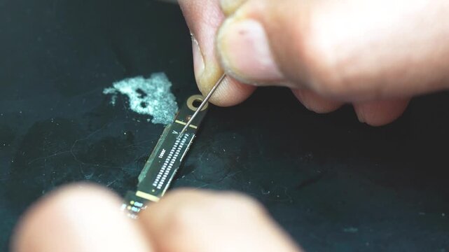 Technician cleaning a circuit board connector with precision tools close up workbench