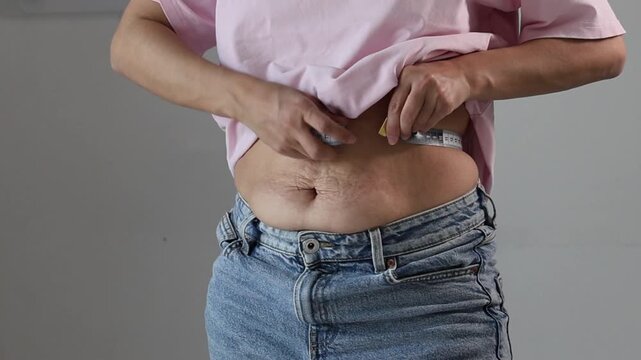 A woman checks her waist size with a measuring tape. Controlling your body size