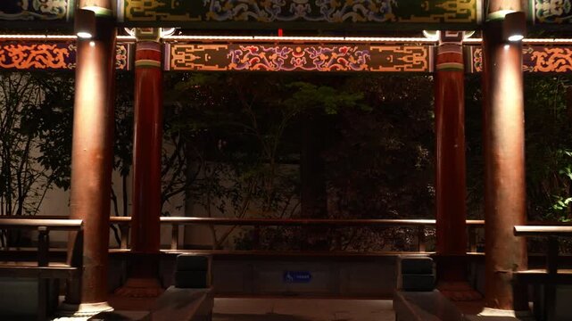 Traditional Chinese architectural gateway corridor at night with illuminated painted beams and columns