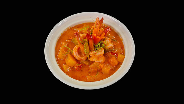 Kaeng Khua Sapparot, traditional Thai red curry with pineapple and shrimp in a decorative golden-rimmed bowl, isolated on black background.