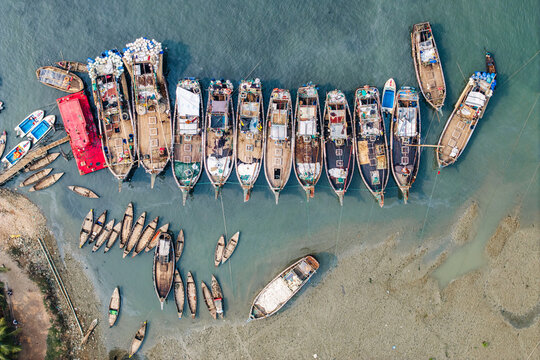 Moheskhali Upazila, Bangladesh - 11 March 2026: Aerial view of traditional wooden fishing boats moored in the shallow turquoise waters along the coast.