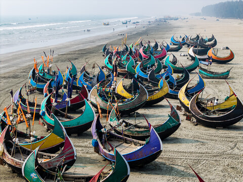 Cox's Bazar, Bangladesh - 10 March 2026: Aerial view of colorful traditional moon boats parked on the sandy shore of the world's longest natural sea beach.