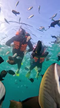 Happy couple in snorkeling mask dive underwater with tropical fishes in coral reef sea in Weh Island Sabang, Indonesia. Show by hands divers sign of love and heart. 