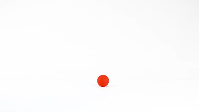 Vibrant Red Plastic Ball Rolling Across a Solid White Studio Background