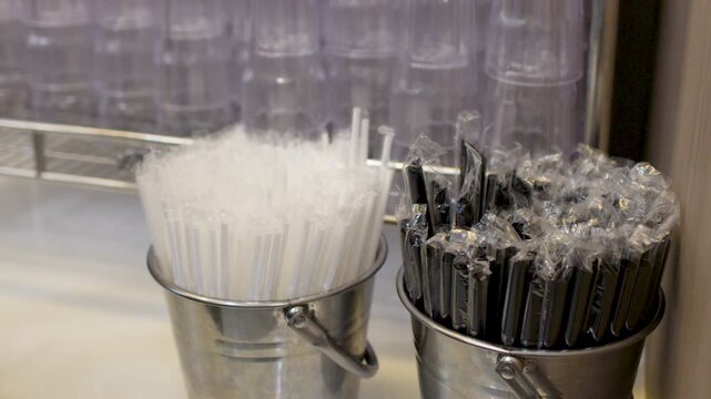 Asian Female Hand Grabbing Plastic Drinking Straws from Metal Bucket