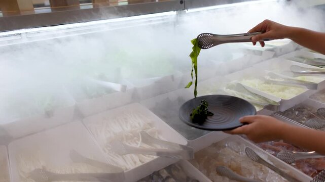 Customer Using Tongs to Select Seaweed at a Fresh Asian Buffet