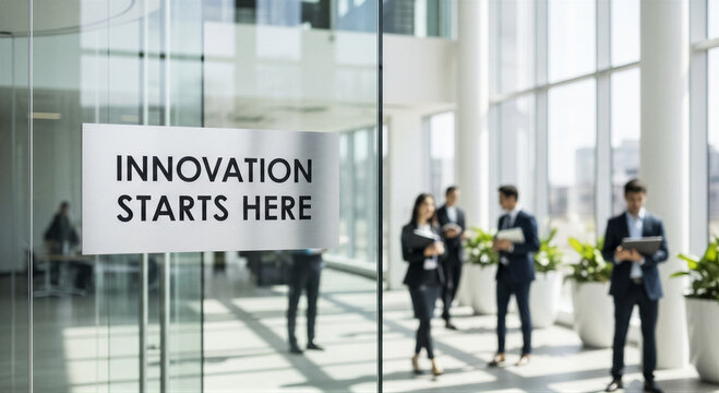 Business people walking in a modern office building with a sign that says innovation starts here on the glass wall