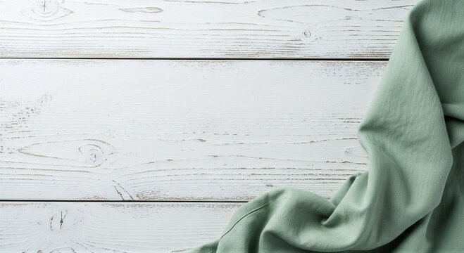 Rustic white wooden table background with a soft sage green linen cloth draped on the right side, top view with copy space