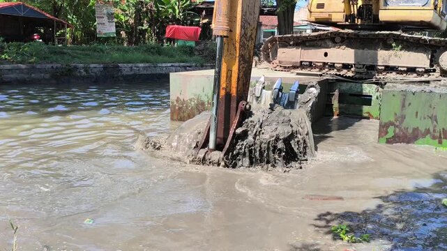 Heavy excavator dredging a river to remove sediment and improve water flow, showcasing large construction equipment working on river maintenance and flood prevention in daylight