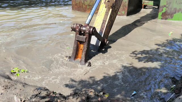 Heavy excavator dredging a river to remove sediment and improve water flow, showcasing large construction equipment working on river maintenance and flood prevention in daylight
