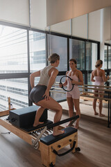 Naklejka premium Pilates instructor guiding woman through standing reformer exercises in modern studio