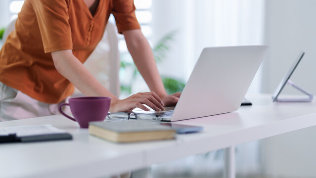 businesswoman standing desk using laptop computer hybrid work morning home office white desk remote working freelancer typing keyboard online learning digital