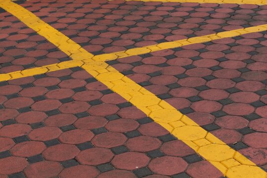Red and black interlocking pavers with bright yellow traffic lines