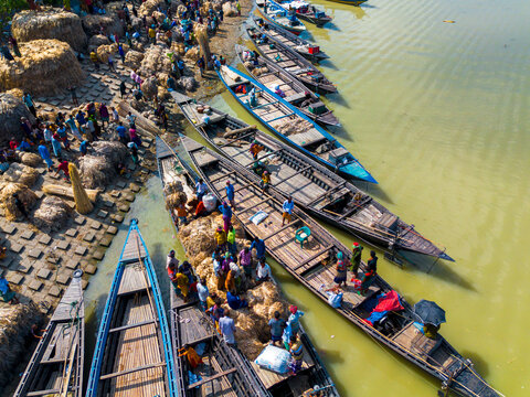 Islampur, Bangladesh - 05 September 2025: Aerial view of people loading large bundles of jute onto traditional wooden boats along the riverbank.