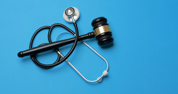 Serious medical gavel and stethoscope representing ethical medicine law justice malpractice and professional healthcare on blue background