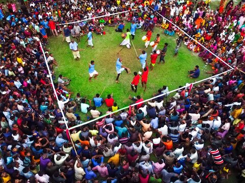 Nilphamari, Bangladesh - 01 May 2026: Aerial view of a traditional Lathi Khela stick fighting performance in a green field surrounded by a large crowd of spectators.