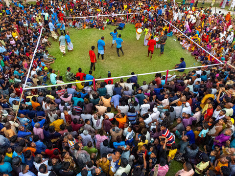 Nilphamari, Bangladesh - 01 May 2026: Aerial view of a large crowd gathered around a grassy arena for a traditional sporting event with drummers and participants.
