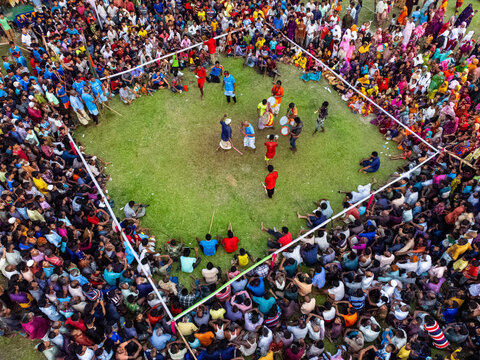 Nilphamari, Bangladesh - 01 May 2026: Aerial view of a traditional stick dance performance in a grassy arena surrounded by a large, colorful crowd of spectators.