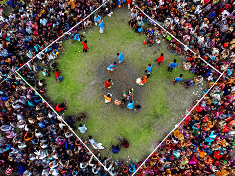 Nilphamari, Bangladesh - 01 May 2026: Aerial view of a large crowd gathered around a square arena for a traditional folk performance on a green field.