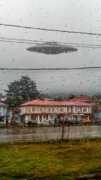 View from moving old bus window rain drops nostalgic 1990s China residential buildings chaotic wires giant white balloon in distance moody emotional film grain chromatic aberration soft focus CCD