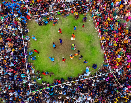 Nilphamari, Bangladesh - 01 May 2026: Aerial view of a traditional folk game performance with a large crowd of people surrounding a square grassy field during a local festival.