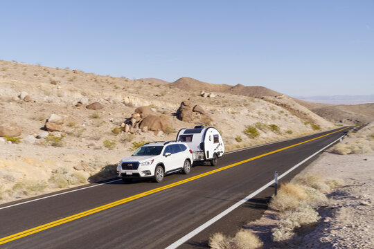 Compact Subaru towing a teardrop RV in the Mojave Desert, California.  