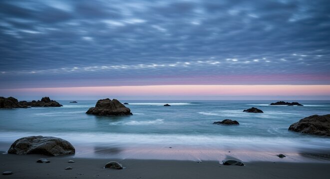 Dramatic layered cloud formations over sea at sunset with rocks in foreground for nature features, coastal real estate marketing and travel editorial