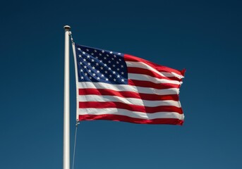 Obraz premium National flag of the United States billowing on a flagpole against a clear blue sky for patriotic campaigns, political advertising and national holiday celebrations