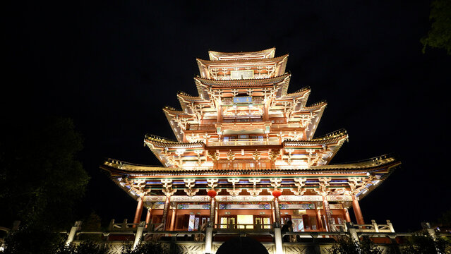 Multi-tiered traditional Chinese pagoda illuminated by night lighting with ornate eaves and wooden architecture